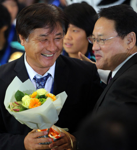 2010 국제축구연맹(FIFA) 17세 이하(U-17) 여자월드컵에서 한국축구 사상 최초로 우승한 여자축구대표팀이 28일 오후 인천국제공항을 통해 귀국한 가운데 최덕주 감독이 유인촌 문화체육관광부장관으로부터 꽃다발을 받고 있다. 연합뉴스