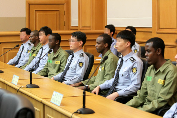 소말리아 해적들이 지난 5월 23일 부산지법 법정에서 법원경찰 사이사이에 앉아 신문을 기다리고 있다. 서울신문은 동료 해적들과 달리 아울 브랄라트(왼쪽 네 번째)만 미성년자여서 얼굴을 모자이크로 처리했다. 부산 연합뉴스