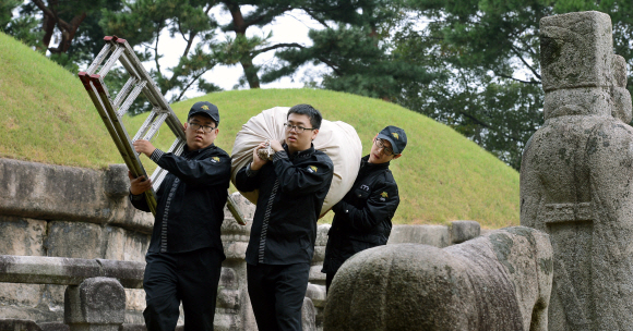 조선 왕릉인 헌인릉(獻仁陵)에서 복무 중인 공익근무요원들이 빗물가리개를 걷는 작업을 마친 후 능에서 내려오고 있다. 공익근무요원제도는 신체검사에서 4급 판정을 받고 국가기관이나 공공단체, 복지시설 등에서 일하는 병역 대체복무제도다.