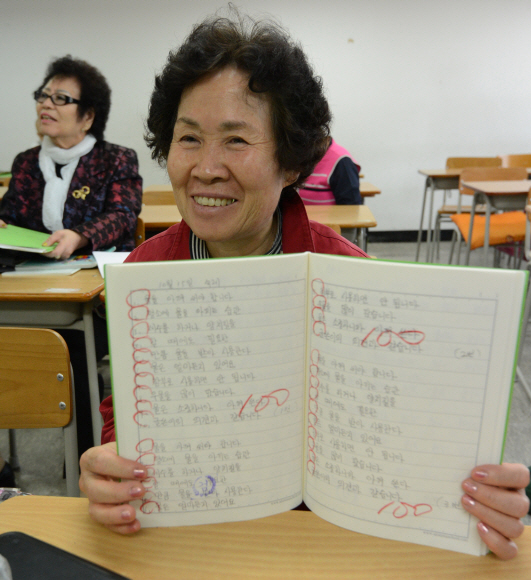 받아쓰기에서 100점을 받고 환하게 웃는 할머니.