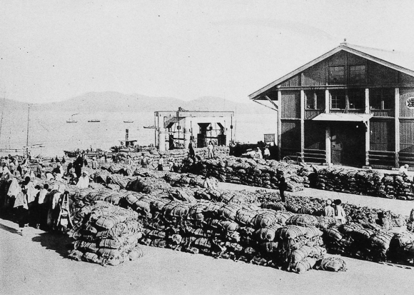 1930년대 일본으로 수탈해 가기 위해 군산 내항에 쌓아 놓은 조선의 쌀가마니들. 항구 쪽으로 뜬다리 부두(부잔교)가 보인다.