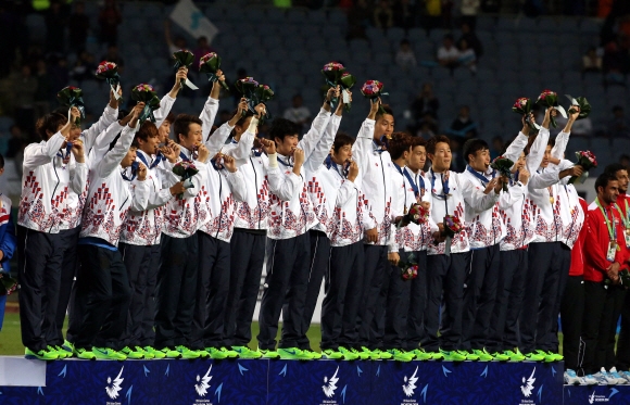 2일 인천문학경기장에서 열린 인천아시안게임 남자 축구 결승전에서 연장 사투 끝에 북한을 꺾고 우승한 한국 대표 선수들이 시상대에서 꽃다발을 치켜들며 팬들의 환호에 답하고 있다.