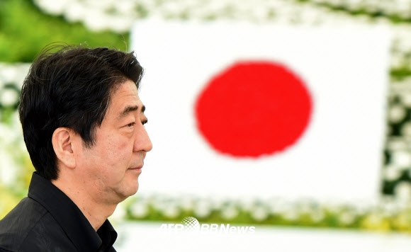 아베 신조(安倍晋三) 일본 총리가 23일(현지시간) 태평양전쟁 오키나와(沖繩) 전투 전몰자 추도식에서 꽃으로 장식된 제단의 국기 앞을 지나가고 있다. ⓒ AFPBBNews=News1
