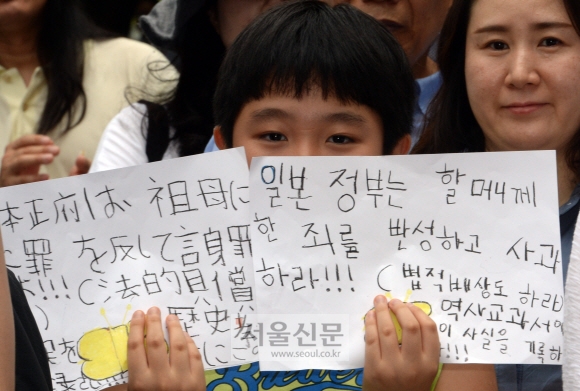 19일 오후 서울 종로구 중학동 주한일본대사관 앞에서 열린 ‘일본군 위안부 피해자 문제 해결을 위한 수요집회’에 참가한 어린이가 일본의 사죄를 촉구하는 메시지를 한국어와 일본어로 적어 들고 있다. 광복 70주년을 맞아 서울신문과 도쿄신문이 공동으로 실시한 여론조사에 따르면 10명 중 8명이 위안부 문제 등 역사인식 차이 때문에 한·일 관계가 악화됐다고 답변했다. 도준석 기자 pado@seoul.co.kr