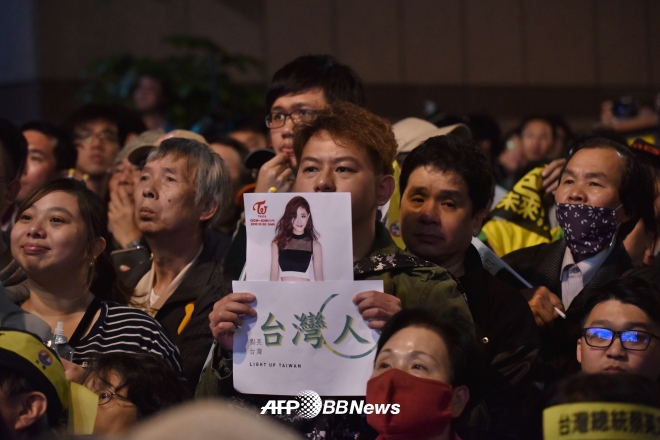 대만 민진당(DPP) 지지자가 대만 국기를 흔들어 논란이 된 쯔위의 사진을 들어보이고 있다. ⓒAFPBBNews=News1