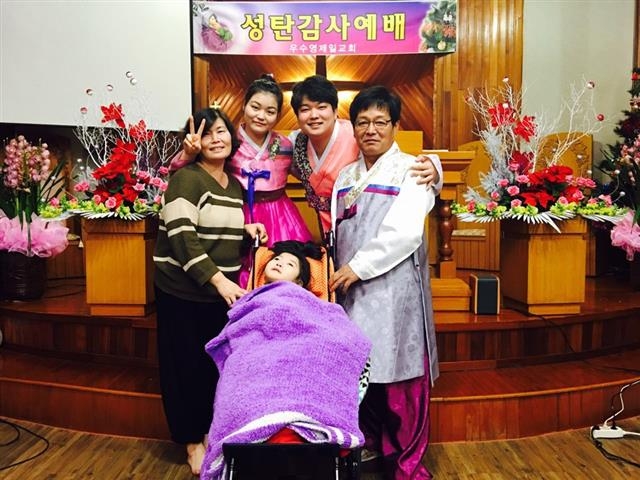 지난해 성탄절 때 이군을 비롯한 가족들이 교회에 모여 휠체어에 누운 여동생 샛별이와 함께 다정한 표정으로 사진을 찍은 모습.