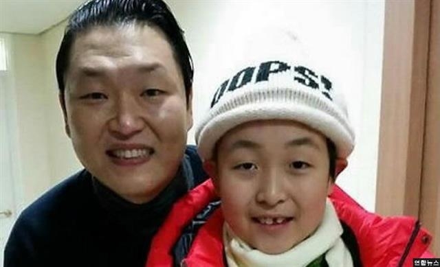 가수 싸이(왼쪽)가 2014년 12월 콘서트 대기실에서 ‘리틀 싸이’ 전민우군과 만나 전군의 쾌유를 빌며 함께 사진을 찍고 있는 모습. 연합뉴스