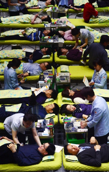 서울시청 소속 공무원들이 19일 시청 대강당에 마련된 간이 침대에 누워 헌혈을 하고 있다. 이날 열린 2016년 상반기 사랑의 헌혈 행사에는 250여명의 공무원이 참여했다. 헌혈증서 517장이 한국백혈병어린이재단에 전달됐다. 박윤슬 기자 seul@seoul.co.kr