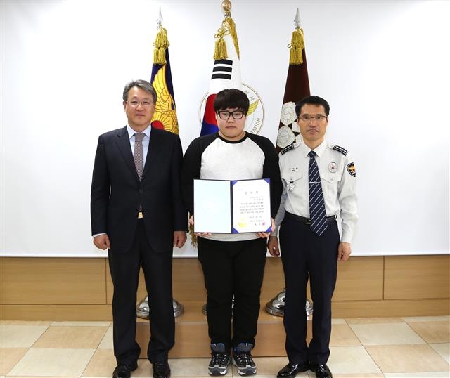 폐지 줍는 할아버지의 분실한 돈을 주워 돌려준 영진전문대생 임호준씨가 23일 대구 북부경찰서에서 감사장을 받은 뒤 기념사진을 찍고 있다. 왼쪽부터 최재영 영진전문대 총장, 임씨, 최석환 대구 북부경찰서장. 영진전문대 제공