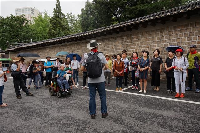 세실극장 건너편 덕수궁 돌담길을 등지고 이필용 해설사로부터 세실극장 지하에 있는 세실 레스토랑을 중심으로 1987년 민주화 투쟁이 시작됐다는 설명을 듣고 있는 모습.