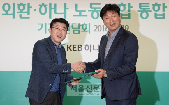 김근용(왼쪽) 외환은행 노조위원장과 김창근 하나은행 노조위원장이 19일 서울 중구 을지로 KEB하나은행 본점에서 노조 통합 합의서에 서명한 뒤 악수하고 있다. 통합 노조는 내년 1월 출범한다. 도준석 기자 pado@seoul.co.kr
