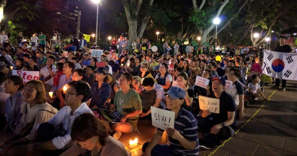 호주 교민 800여명이 12일(현지시간) 시드니 도심 하이드 파크에서 ‘박근혜 OUT’ 등 구호가 적힌 피켓과 대형 태극기 등을 들고 촛불시위에 참여하고 있다. 시드니 연합뉴스