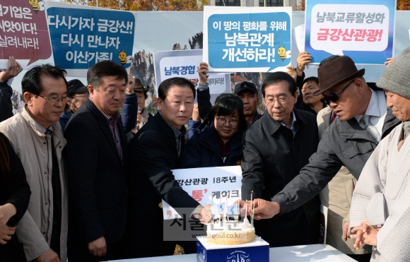 18일 오전 정부서울청사 정문 앞에서 금강산기업인협의회, 남북경협기업비상대책위원회가 금강산관광 18 주년을 맞아 남북경협과 금강산관광 재개를 정부에 요청하는 ’다시 가자, 금강산!’ 기자회견에서 박원순 시장과 참석자들이 남북 소통의 염원을 담은 ’소통케이크’에 초를 꼽고 있다. 강성남 선임기자 snk@seoul.co.kr