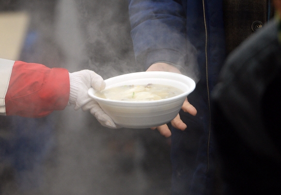 2일 서울 용산구 서울역광장에서 대한적십자 임직원 및 봉사원들이 노숙인 및 독거노인에게 떡국을 나눠주고 있다.  박윤슬 기자 seul@seoul.co.kr