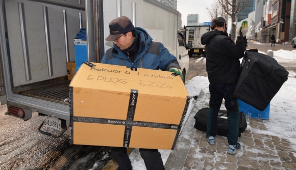 한 택배기사(오른쪽)가 20일 오전 서울 강남구의 눈 쌓인 인도에서 배송차량에 상자를 전달한 뒤 또 다른 곳에 택배를 하기 위해 서둘러 행낭을 둘러메고 있다. 박지환 기자 popocar@seoul.co.kr