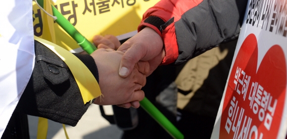 박근혜 대통령의 탄핵을 촉구하며 1인 시위를 하는 시민과 탄핵 반대 1인 시위를 하는 시민이 7일 서울 종로구 헌법재판소 앞에서 설전(舌戰)을 벌이다 손을 맞잡았다. 박윤슬 기자 seul@seoul.co.kr