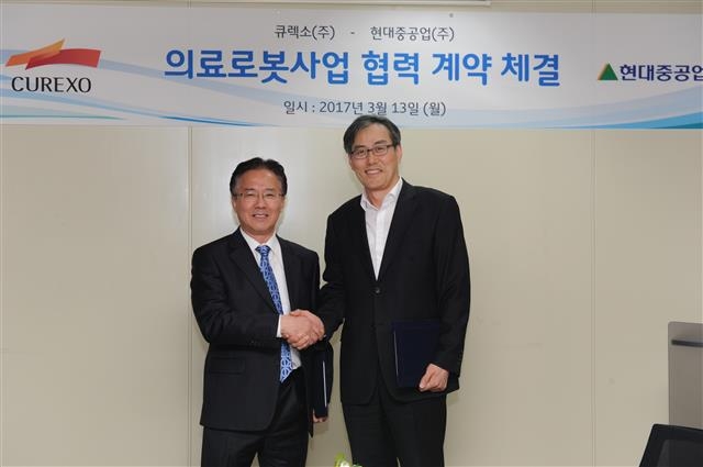 13일 서울 서초구 잠원동 큐렉소 본사에서 열린 협약식에서 정성현(왼쪽) 현대중공업 상무와 이재준 큐렉소 대표가 기념 촬영을 하고 있다. 큐렉소 제공