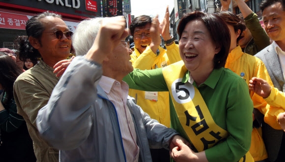 심상정(오른쪽) 정의당 대선 후보가 7일 충북 청주시 성안길에서 열린 유세에서 파이팅을 외치는 시민의 손을 잡고 어깨에 손을 올리며 활짝 웃고 있다. 청주 연합뉴스