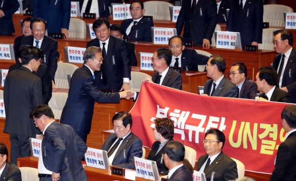 한 손은 현수막, 한 손은 악수