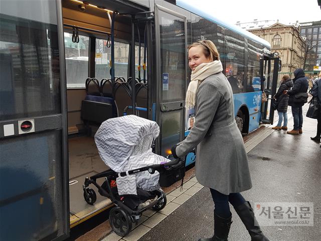 지난달 30일(현지시간) 핀란드 헬싱키 센트럴스테이션 앞 버스 정류장에서 피리타 발코넨이 아이를 태운 유모차와 함께 버스 후문으로 탑승하고 있다. 헬싱키에서는 유모차를 동반하면 대중교통 운임료를 내지 않아도 된다. 헬싱키 박재홍 기자 maeno@seoul.co.kr