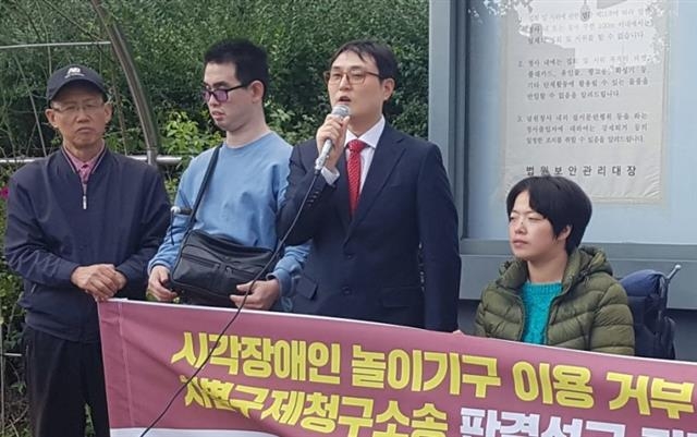 지난 11일 시각장애인 등이 에버랜드를 상대로 낸 손해배상 청구 소송에서 원고 일부 승소 판결을 받은 뒤 김재왕(가운데) 변호사와 함께 기자회견을 하는 모습.  공익인권변호사모임 희망을 만드는 법 제공