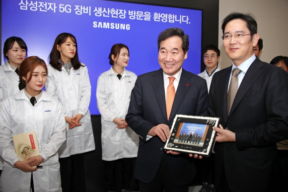 10일 경기 수원시 삼성전자 5G 장비 생산 현장을 방문한 이낙연(오른쪽 두 번째) 국무총리와 이재용(오른쪽) 삼성전자 부회장이 기념사진을 들고 미소 짓고 있다. 연합뉴스