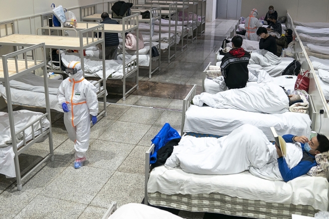 5일 중국 후베이성 우한의 한 대형 전시장을 개조한 임시병원에서 보호복을 입은 의료진이 신종 코로나바이러스 감염증 환자들 옆을 지나가고 있다. 2020.2.5 로이터 연합뉴스