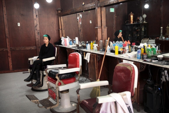 코로나19의 확산을 막기 위한 봉쇄 조치로 세계 각국은 경제활동이 사실상 마비되면서 수십년 만에 최악의 실업대란을 겪고 있다. 코로나19 확산세가 꺾인 일부 국가들이 조심스럽게 봉쇄 조치를 풀고 있지만 불안감에 얼어붙은 소비심리는 좀처럼 회복되지 않고 있다. 지난 13일 영업을 재개한 미국 인디애나주 체스터턴의 이발소에서 여성 직원이 텅 빈 가게에 혼자 앉아 손님을 기다리고 있다. 체스터턴(미 인디애나주) 게티/AFP 연합뉴스