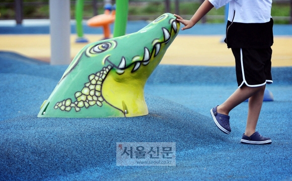 한 어린이가 운영중단된 물놀이장의 악어모형과 인사하듯 손을 대고 있다.