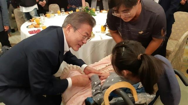 문재인 대통령이 2018년 9월 청와대에서 열린 발달장애인 초청 간담회에서 중증복합 장애인 김유진(23)씨의 손을 맞잡고 있다. 오른쪽 위는 어머니 김신애씨. 김신애씨 제공