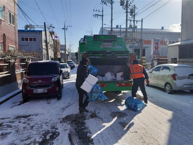 서울에 한파경보가 발령된 지난 8일 경기 안산의 한 골목에서 청소 노동자 김만석(오른쪽)씨가 동료와 함께 재활용 쓰레기를 수거 차량에 싣고 있다. 김만석씨 제공