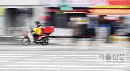 서울 강남구 논현역 인근 횡단보도에서 한 배달 오토바이가 보행자 신호에 횡단보도를 건너는 사람들 사이를 지나가며 신호를 위반하고 있다.