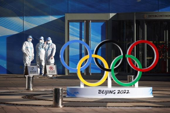 2022 베이징동계올림픽 개·폐막식이 열리는 베이징 국가경기장 인근 공사 현장에서 방역복을 입은 직원들이 오륜 상징물 옆에서 대기하고 있다. 베이징 로이터 연합뉴스