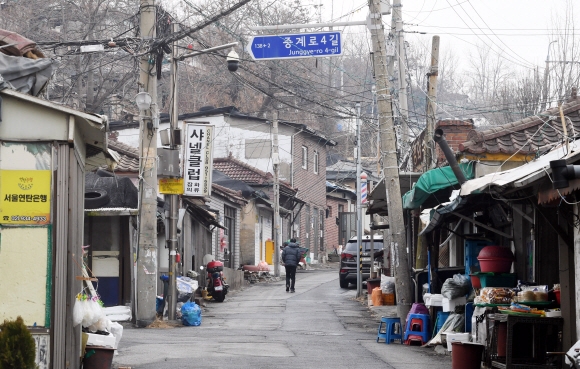 영화 세트장 같은 비탈진 마을길을 노인이 힘겹게 오르고 있다.