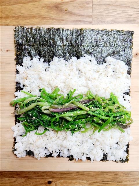 4. 소금, 참기름, 깨소금으로 양념한 밥을 김에 편 다음 미나리를 올리고 김밥을 말아 준 뒤 먹기 좋은 크기로 썬다.