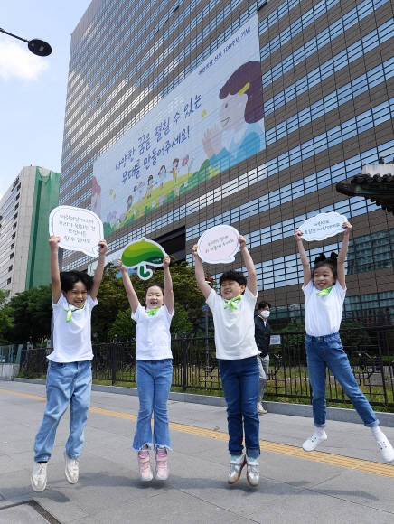 어린이날을 사흘 앞둔 2일 서울 종로구 교보생명빌딩 외벽에 ‘어린이 말씀’을 담은 초대형 현수막이 걸린 가운데 마스크를 벗은 아이들이 하늘 높이 뛰어오르고 있다. 초록우산어린이재단과 함께 기획한 이번 래핑은 어린이를 하나의 인격체로 존중하자는 의미를 담았다. 2022.5.2 오장환 기자