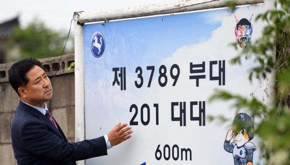 지난 30일 이지문 한국청렴운동본부 이사장이 30년 전 자신이 근무했던 부대 방향을 가리키는 표지판을 바라보며 감회에 잠겨 있다. 부대 앞을 배경으로 사진 한 장 찍는 것도 쉽지 않은 곳이다. 그는 “정말 언젠가 꼭 한 번은 들어가 옛 흔적을 찾아보고 싶다”고 말했다. 박윤슬 기자
