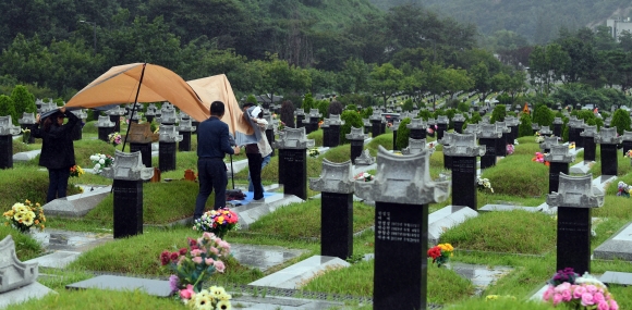 추석을 앞두고 4일 인천 부평구 인천가족공원을 찾은 한 가족이 성묘를 위해 천막을 치려다 빗줄기와 바람때문에 다시 철수하고 있다. 2022. 9. 4 박윤슬 기자