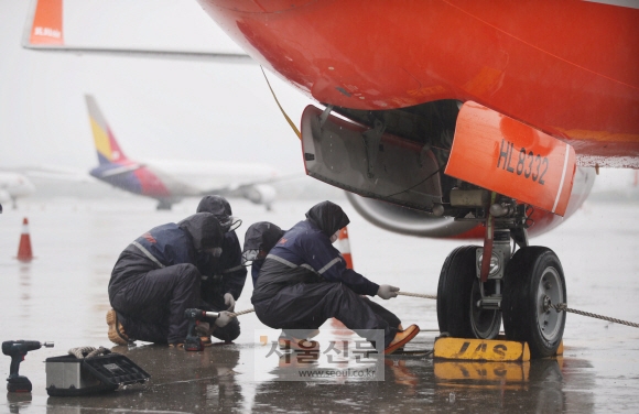 제11호 태풍 ‘힌남노’가 북상 중인 5일 항공사 직원들이 김포국제공항 계류장에서 항공기 바퀴를 고정하는 결박 작업을 하고 있다. 안주영 전문기자