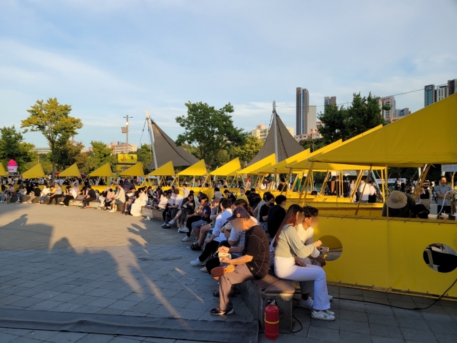 18일 서울 서초구 한강공원에서 열린 ‘한강달빛공원’ 야시장에서 시민들이 푸드트럭 음식을 즐기고 있다. 신융아 기자