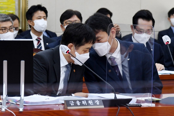 김주현(왼쪽) 금융위원장과 이복현 금융감독원장이 24일 국회에서 열린 정무위원회 국정감사에서 긴밀히 이야기를 나누고 있다. 채권시장을 공포로 몰아넣은 ‘레고랜드 사태’와 관련해 금융당국의 대처가 늦었다는 비판이 나온다. 국회 공동사진취재단