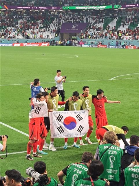 한국 축구대표팀 선수들이 지난 3일(한국시간) 카타르 알라이얀 에듀케이션 시티 스타디움에서 열린 2022 카타르월드컵 포르투갈전에서 승리한 후 김의민씨가 ‘중요한 것은 꺾이지 않는 마음’ 등의 문구를 적어 던진 태극기를 들고 있다. 김의민씨 제공