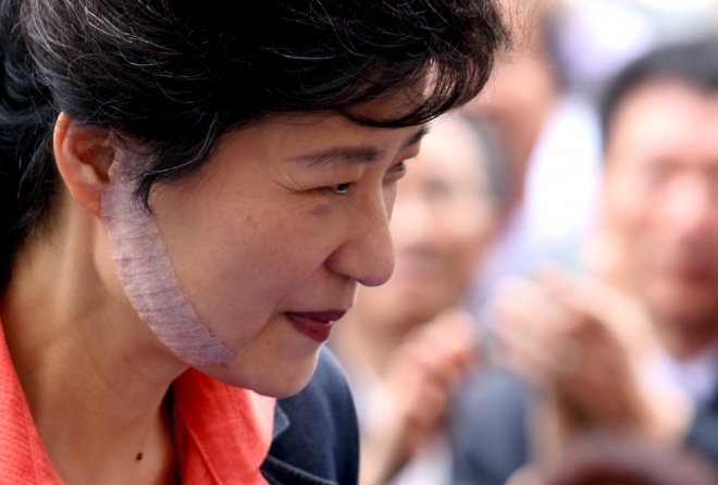 피습사건 이후 병상에 있다 퇴원한 박근혜 한나라당 대표가 살색 밴드로 오른쪽 뺨 수술부위를 가린채 29일 대전시 서구 둔산동 박성효 대전시장 후보 사무실을 찾아 지지자들에게 인사하기위해 임시연단에 오르며 미소를 보이고 있다. 2006.5.29 연합뉴스