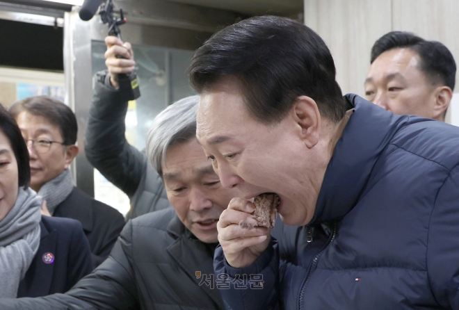 윤석열 대통령이 25일 경기도 의정부시 의정부제일시장을 찾아 떡 가게에서 상인이 건넨 떡을 맛보고 있다. 2024.1.25 연합뉴스