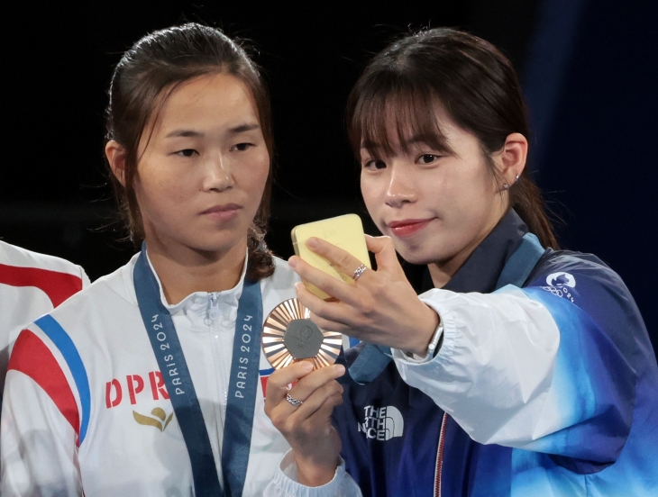 2024 파리 올림픽 복싱 여자 54㎏급에서 동메달을 획득한 우리나라 임애지(오른쪽)와 북한 방철미가 8일(현지시간) 프랑스 파리 롤랑가로스 경기장에서 열린 시상식에서 ‘셀카 세리머니’를 하고 있다. 2024.8.9 연합뉴스 2024 파리 올림픽 복싱 여자 54㎏급에서 동메달을 획득한 우리나라 임애지(오른쪽)와 북한 방철미가 8일(현지시간) 프랑스 파리 롤랑가로스 경기장에서 열린 시상식에서 ‘셀카 세리머니’를 하고 있다. 2024.8.9 연합뉴스