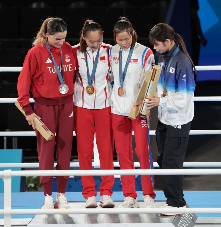 8일(현지시간) 프랑스 파리 롤랑가로스 경기장에서 열린 2024 파리 올림픽 복싱 여자 54㎏급 메달 수여식 후 ‘셀카 세리머니’를 할 때 우리나라 임애지(맨 오른쪽)가 금메달리스트 단상에 바로 올라가지 못하고 머뭇거리자 북한 방철미(오른쪽 두 번째)가 올라오라는 손짓을 하고 있다. 2024.8.9 연합뉴스 8일(현지시간) 프랑스 파리 롤랑가로스 경기장에서 열린 2024 파리 올림픽 복싱 여자 54㎏급 메달 수여식 후 ‘셀카 세리머니’를 할 때 우리나라 임애지(맨 오른쪽)가 금메달리스트 단상에 바로 올라가지 못하고 머뭇거리자 북한 방철미(오른쪽 두 번째)가 올라오라는 손짓을 하고 있다. 2024.8.9 연합뉴스