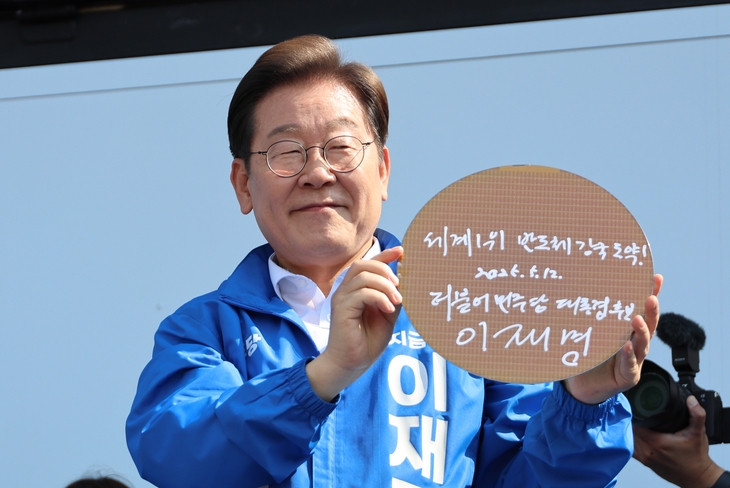 더불어민주당 이재명 대선 후보가 12일 경기 화성시 동탄 센트럴파크 음악분수중앙광장 유세장에서 ‘세계1위 반도체 강국 도약!’이라고 쓴 반도체 웨이퍼를 들어 보이고 있다. 연합뉴스